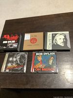 Five music CD sets by Bob Dylan and Tom Petty on a wooden surface.