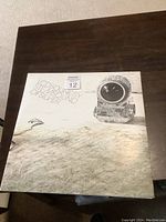 Front album cover showing textured design with embedded lens artwork and album title