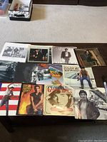 Photo showing multiple Bruce Springsteen album covers and other records spread on a table including notable Bruce Springsteen portraits.