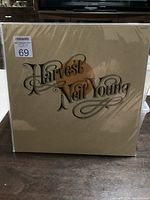 Front cover of the sealed vinyl album showing 'Harvest Neil Young' title in stylized script on beige background.