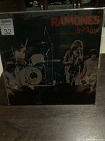 Front cover of the sealed Ramones It's Live vinyl LP showing band live performance and title text.