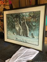 Framed print showing two deer in snow with dark forest background. Signature and numbering visible bottom right.
