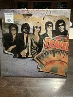 Front cover of The Traveling Wilburys vinyl album showing the band members' images and album title with some edge wear.