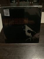 Front cover of the sealed U2 Rattle and Hum double vinyl album showing the dark artwork with title and silhouette image.