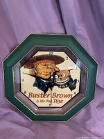 Full view of the octagonal vintage wall clock with green frame and Buster Brown and his dog Tige illustration.