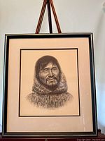 Framed portrait of Inuit man in fur parka displayed on an easel.