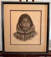 Frontal image of framed Inuit art charcoal portrait representing an elderly Inuit man in a fur-lined hooded parka. The contrast captures the texture and facial details.