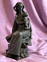 Front side view of signed stone carving sculpture of a seated woman holding a child on lap.