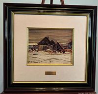 Framed artwork of a winter village scene by A.Y. Jackson showing the entire piece within a dark wooden frame with beige matting, including plaque below image.
