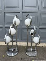 Photo showing front angle of both lamps, the right lamp missing its top glass globe shade and the left intact