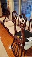 Row of mahogany shield-back dining chairs, two armchairs at ends and several side chairs lined up