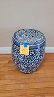 Full view of the blue and white ceramic stool with floral and geometric patterns, showing its size and shape.