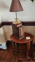 Photo of vintage book-styled lamp on top of the round side table with book-style legs.