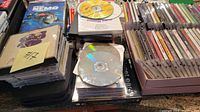 Photo of mixed CDs and DVDs showing various jewel cases and DVD cases with some visible discs including Finding Nemo DVD.