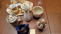 Overview of ceramic tea set with tray, cream pitcher, sugar bowl, vase, two lidded jars, blue cup