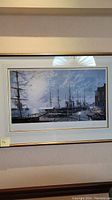 Frontal view of framed print showing harbor scene with multiple tall ships and waterfront buildings