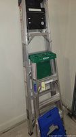 Image showing three ladders: one aluminum Werner brand step ladder and two folding plastic step stools in green and blue.