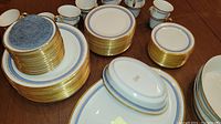 Stacks of large dinner plates, medium salad plates, small saucers and bowls arranged on wooden table