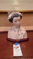 Full front view of the porcelain geisha bust on its wooden base