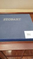 Blue hardcover Stobart book with slipcase seen from above, showing the gold embossed 'STOBART' on the cover.