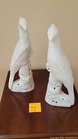 Front view showing both white ceramic bird sculptures side by side on tabletop