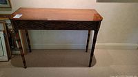Front view of vintage wooden sofa table showing decorative aprons and tapered bamboo-style legs.