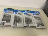 Four new 4x10 inch floor registers in original packaging, silver metal with vent louvers visible.