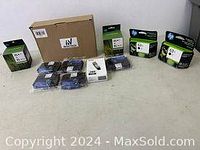 Full view of several black and color ink cartridges in original boxes on white surface.