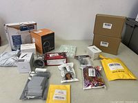 Overview photo showing multiple lighting and electrical accessory items in original packaging arranged on a table.