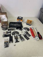 Complete view of lot showing all items including black multi-tool blades, rolls of tape, pouch and roller tools.