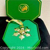 Photo of Swarovski crystal snowflake ornament inside green presentation box with gold-tone logo.