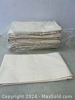 Stack of approximately 12 white or off-white flat sheets, folded and packaged in plastic wrap.