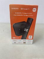 Front of sealed box showing Xiaomi TV Box S 2nd Gen branding, device and remote image, supported apps and 4K UHD label.