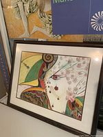 Framed colorful abstract bird print displayed horizontally showing intricate, multicolored patterns on the bird and surrounding floral designs.