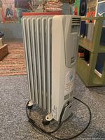 Side angle showing the radiator heater's fins, wheels, power cord, and part of the control panel