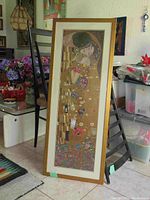 Full view of the framed Klimt print leaning against a chair, showing the artwork and surroundings.