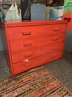 Front angled view of large red wood dresser showing four drawers and horizontal pull handles.