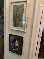 Two framed floral prints mounted on wall, one white framed rectangular print and one black framed print with oval mat.