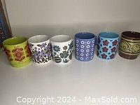 Front row shot displaying six unique vintage mugs with different mid-century modern floral and abstract patterns.