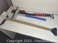 Photo of three car ice scrapers placed on a white surface, showing different designs and handle materials