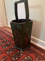 Side view showing hexagonal wooden umbrella stand on patterned rug with floral and urn painted decorative panels
