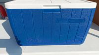 Exterior view of blue cooler with white lid and Coleman logo