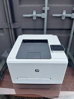 Front view of the white HP Color LaserJet Pro M254dw printer showing the paper output slot and control panel.