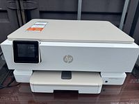 Front view of white HP Envy Inspire printer showing touchscreen panel and output tray.