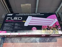 Photo of the unopened box of a 2ft LED plant grow light showing brand "Ocean Master" and key features like red spectrum enrichment for budding and flowering, 60W power.