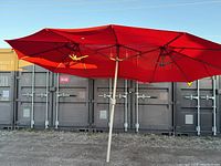 Fully extended large red rectangular canvas umbrella with metal arm supports and central pole outdoors