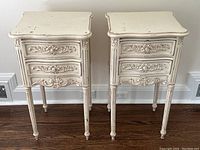Front view of both matching white painted nightstands showing carved drawer fronts and distressed finish