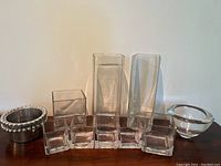 Front view of glass vases and wine bottle coasters arranged side by side, showing shapes, sizes and condition.