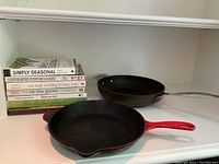 Photo showing both frying pans and a stack of cookbooks
