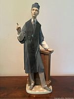 Front view of the Lladro porcelain barrister figurine showing black legal gown and pointing hand with broken finger.